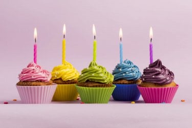 illuminated-candles-colorful-muffins-against-pink-backdrop.jpg